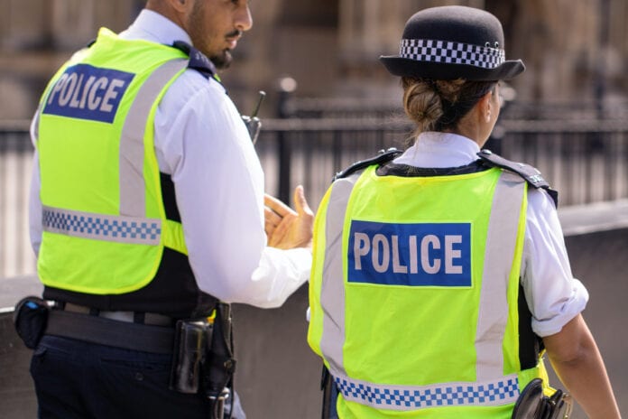 Male and female Asian metropolitan police officers patrol the crowds of tourists outside the Hoses of Parliament in Westminster, London, UK