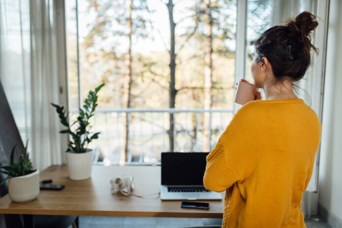 Young freelancer taking a coffee break at her home office