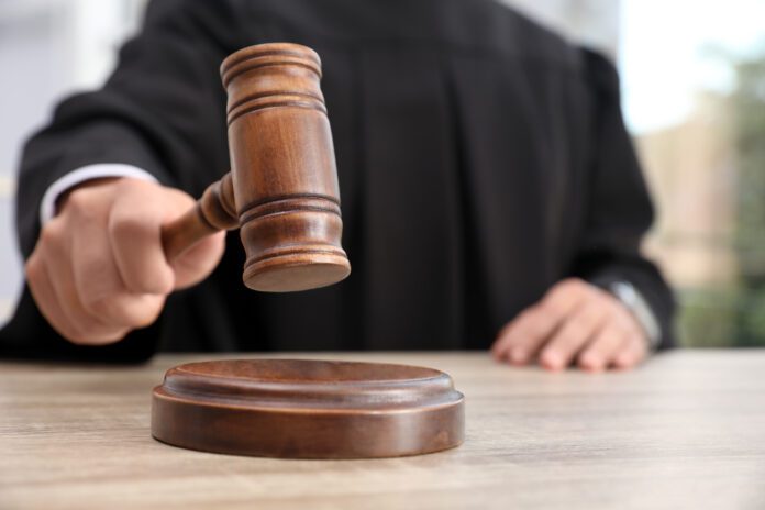 Judge with gavel at wooden table indoors, closeup. Criminal law